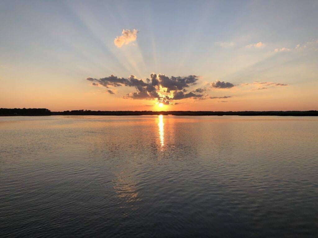 A serene sunset casts vibrant hues over a tranquil lake, reflecting the colorful sky in its calm waters.